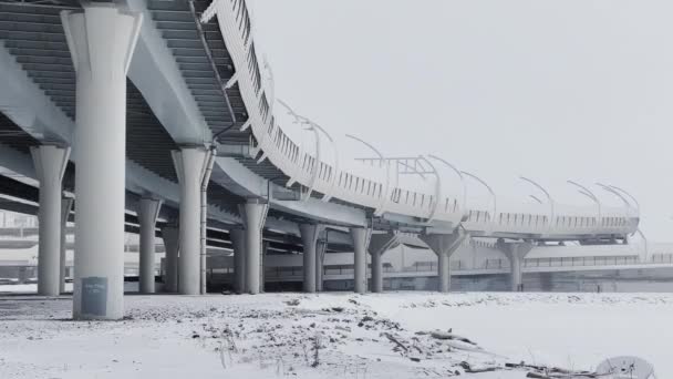 Pilares sob uma estrada de alta velocidade em um dia de inverno, uma ponte de cabo-permanecido na neblina nevada no fundo, sem pessoas — Vídeo de Stock