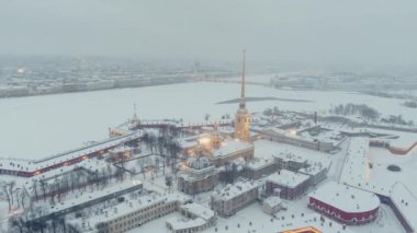 Bir kış akşamı kar fırtınasında Peter ve Paul Kalesi 'nin hava görüntüleri, gece aydınlatması Petropavlos Katedrali altın ışıkla parıldıyor, arka planda St. Petersburg manzarası var.