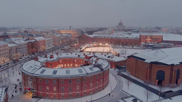 Aerial view of the New Holland park in a snowy winter evening, night illumination of buildings and streets, night cityscape, outdoor skating rink, landmarks of St. Petersburg on a background — Stock Video