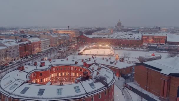 雪に覆われた冬の夜、建物や通りの夜の照明、夜の街並み、屋外スケートリンク、背景にサンクトペテルブルクのランドマーク — ストック動画