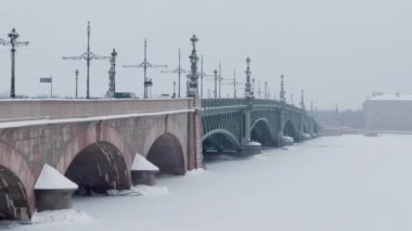 Troitsky Köprüsü bir kış günü kar fırtınasında, donmuş Neva Nehri, köprüde arabaları hareket ettiriyor.