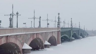 Troitsky Köprüsü bir kış günü kar fırtınasında, donmuş Neva Nehri, köprüde arabaları hareket ettiriyor.
