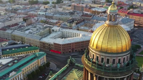 Воздушный утренний городской пейзаж с золотым куполом Исаакиевского собора на восходе солнца, колонны и крест церкви, отражение солнца, спокойствие — стоковое видео