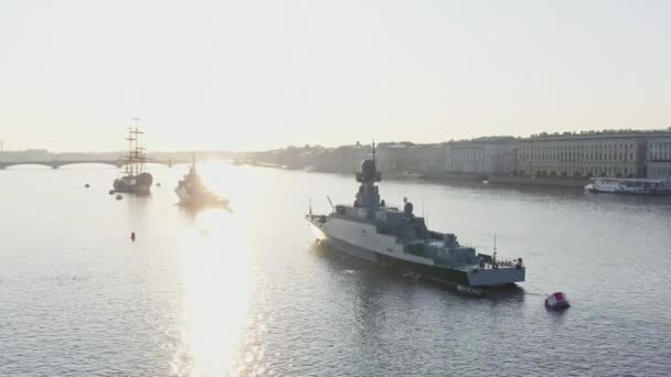 Aerial morning cityscape with warships in the waters of the Neva River before the holiday of the Russian Navy at sunrise, the latest cruisers among the sights, Peter and Paul fortress on a background — Stock Video