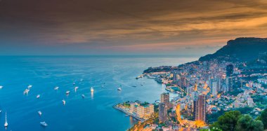 Birçok yat ve gece aydınlatmalı motorlu tekne Akdeniz 'e demirlemiş durumda. Monako Körfezi' nin havadan görünüşü, alacakaranlıkta Monte-Carlo, gece aydınlatmalı şehir manzarası.