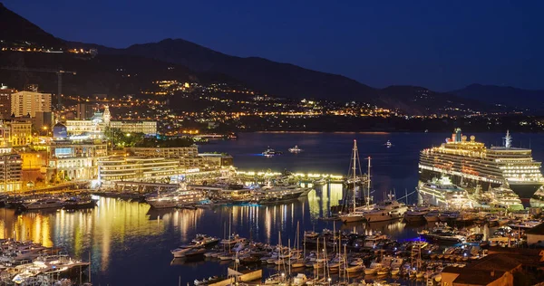 Vista aérea del puerto de Hércules en Mónaco Monte Carlo al atardecer, una gran cantidad de yates y barcos están amarrados en el puerto deportivo, paisaje urbano con iluminación nocturna, reflexión mágica sobre el agua, la montaña, el mar Mediterráneo — Foto de Stock