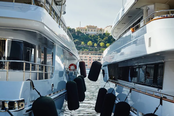 Mónaco, Montecarlo, dos grandes yates a motor están estacionados uno al lado del otro en el puerto, con enormes defensas entre ellos para evitar colisiones en el día soleado, amarres van en el agua azul — Foto de Stock