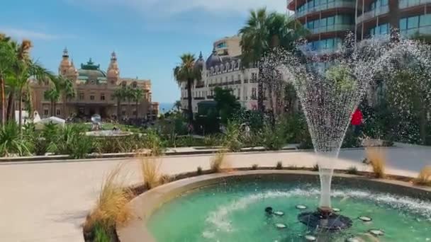 Μονακό, Monte-Carlo, 01 Οκτωβρίου 2019: Η πλατεία Καζίνο Monte-Carlo σε ηλιόλουστη μέρα, το ξενοδοχείο το Παρίσι, νέα κρήνη μπροστά από την πλατεία, οι τουρίστες λαμβάνουν φωτογραφίες από το ορόσημο, πεύκα — Αρχείο Βίντεο