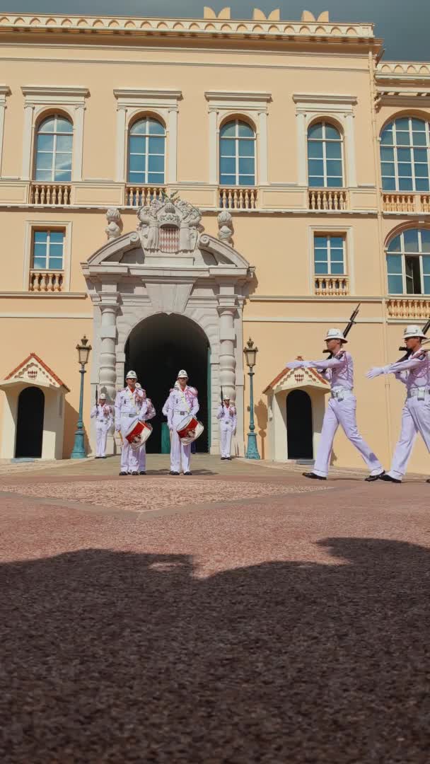 Monaco, Óváros, 2019. szeptember 27.: Függőleges felvétel a monacói herceg palotája őreinek ünnepélyes váltásáról napsütéses napon, fehér egyenruha, régi hagyomány, palota homlokzata, fegyver — Stock videók