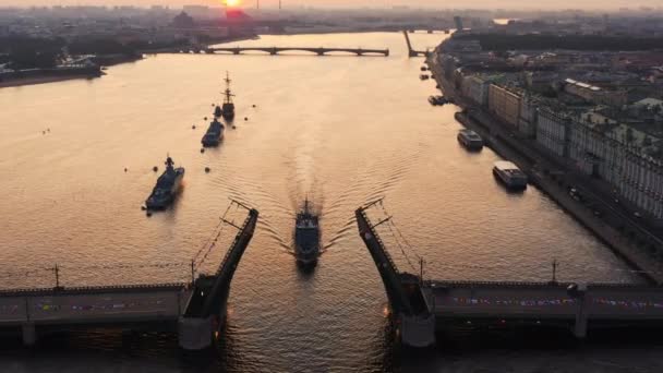 早朝にロシア海軍の休日の前にネヴァ川で軍艦と空中の風景、軍艦は上昇ドローブリッジ、ランドマークの中で最新の巡洋艦の下を通過し、宮殿橋 — ストック動画