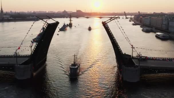 Krajobraz powietrzny z okrętami wojennymi w rzece Neva przed świętem rosyjskiej marynarki wojennej wczesnym rankiem, okręty wojenne przechodzą pod podniesionym mostem zwodzonym, najnowsze krążowniki wśród zabytków, most pałacowy — Wideo stockowe