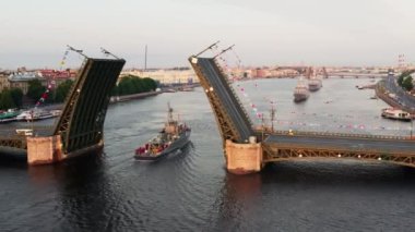 Sabahın erken saatlerinde Rus donanmasının bayramından önce Neva Nehri 'ndeki savaş gemileriyle hava manzarası yükseltilmiş bir asma köprünün altından geçen savaş gemileri, saray köprüsünün en son kruvazörleri.