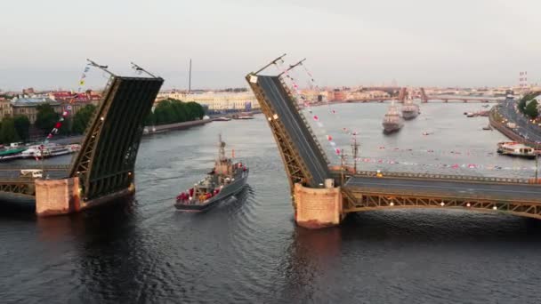 早朝にロシア海軍の休日の前にネヴァ川で軍艦と空中の風景、軍艦は上昇ドローブリッジ、ランドマークの中で最新の巡洋艦の下を通過し、宮殿橋 — ストック動画
