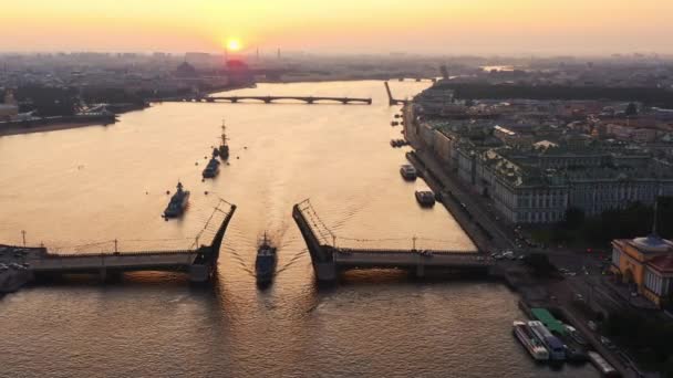 Paisaje aéreo con buques de guerra en el río Neva antes de las vacaciones de la Marina de Rusia en la madrugada, buques de guerra pasan por debajo de un puente levadizo elevado, los últimos cruceros entre los puntos de referencia, Puente del Palacio — Vídeos de Stock