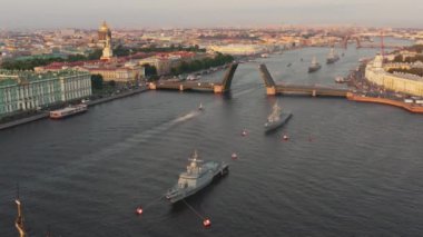 Sabahın erken saatlerinde Rus donanmasının bayramından önce Neva Nehri 'ndeki savaş gemileriyle hava manzarası yükseltilmiş bir asma köprünün altından geçen savaş gemileri, saray köprüsünün en son kruvazörleri.