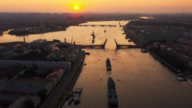 Sabahın erken saatlerinde Rus donanmasının bayramından önce Neva Nehri 'ndeki savaş gemileriyle hava manzarası yükseltilmiş bir asma köprünün altından geçen savaş gemileri, saray köprüsünün en son kruvazörleri.