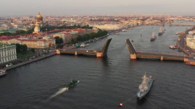 Sabahın erken saatlerinde Rus donanmasının bayramından önce Neva Nehri 'ndeki savaş gemileriyle hava manzarası yükseltilmiş bir asma köprünün altından geçen savaş gemileri, saray köprüsünün en son kruvazörleri.