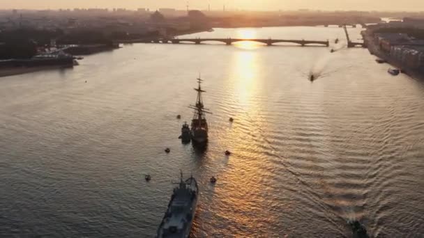 Krajobraz powietrzny z okrętami wojennymi w rzece Neva przed świętem rosyjskiej marynarki wojennej wczesnym rankiem, okręty wojenne przechodzą pod podniesionym mostem zwodzonym, najnowsze krążowniki wśród zabytków, most Trinity — Wideo stockowe