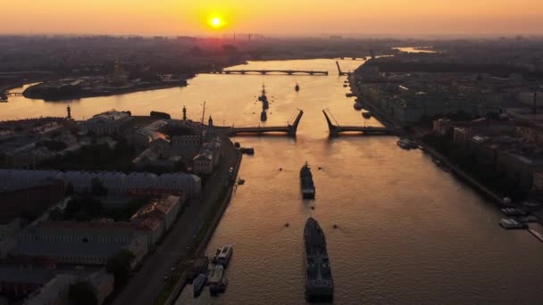 Krajobraz powietrzny z okrętami wojennymi w rzece Neva przed świętem rosyjskiej marynarki wojennej wczesnym rankiem, okręty wojenne przechodzą pod podniesionym mostem zwodzonym, najnowsze krążowniki wśród zabytków, most pałacowy — Wideo stockowe