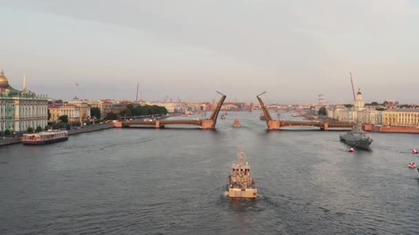 Flyglandskap med krigsfartyg i Neva floden före semestern i den ryska flottan tidigt på morgonen, krigsfartyg passerar under en upphöjd vindbrygga, de senaste kryssare bland landmärken, Palace Bridge — Stockvideo