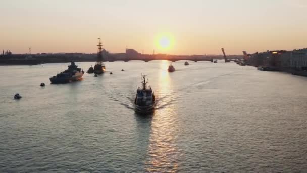 Luchtlandschap met oorlogsschepen in de Neva Rivier voor de vakantie van de Russische marine in de vroege ochtend, oorlogsschepen passeren onder een verhoogde ophaalbrug, de nieuwste cruisers onder bezienswaardigheden, Trinity brug — Stockvideo