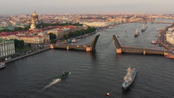 Flyglandskap med krigsfartyg i Neva floden före semestern i den ryska flottan tidigt på morgonen, krigsfartyg passerar under en upphöjd vindbrygga, de senaste kryssare bland landmärken, Palace Bridge — Stockvideo
