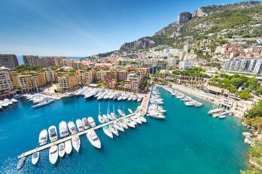 Port Fontvieille 'in panoramik görüntüsü - Monaco, Monaco Ville' in manzarası, azur suyu, güneş ışığı, güneşli bir günde liman, lüks daireler, bir sürü yat ve tekne, dağ manzarası