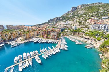 Port Fontvieille 'in panoramik görüntüsü - Monaco, Monaco Ville' in manzarası, azur suyu, güneş ışığı, güneşli bir günde liman, lüks daireler, bir sürü yat ve tekne, dağ manzarası