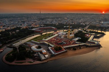 Güneş doğarken Peter ve Paul Kalesi, sudaki portakal ve pembe gökyüzünün yansıması, asma köprüler Troitsky ve Liteiny ayrılır.