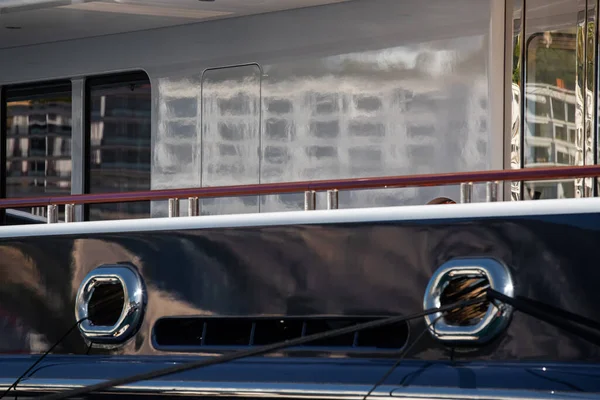 The top deck of a huge yacht at sunny day, glossy board of the boat, The chrome plated handrail, megayacht is moored in port, sun reflection on glossy board