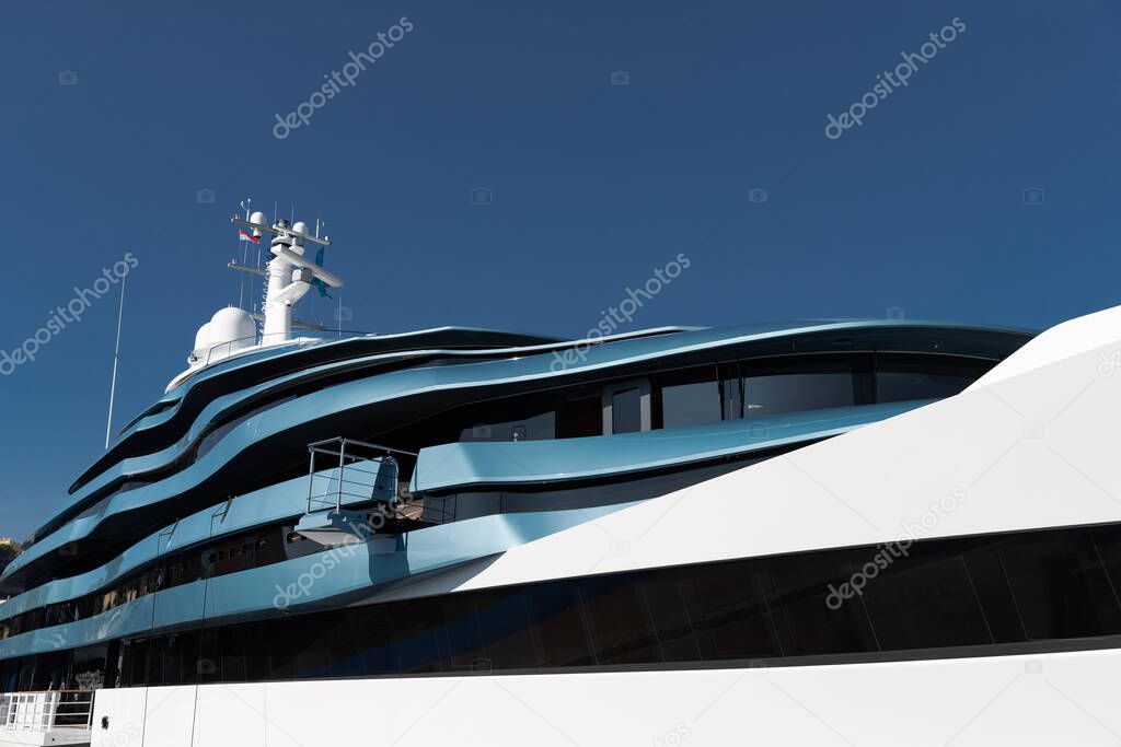 Bottom view of decks of huge yacht of blue color at sunny day, glossy board of the motor boat, sun reflection on glossy board, blue sky is on background