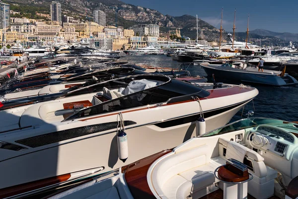 Una gran cantidad de barcos a motor en filas están en el puerto de Mónaco en el día soleado, Monte Carlo, la montaña está en el fondo, colorido interior del barco, están amarrados en el puerto deportivo, reflejo del sol en el tablero brillante — Foto de Stock