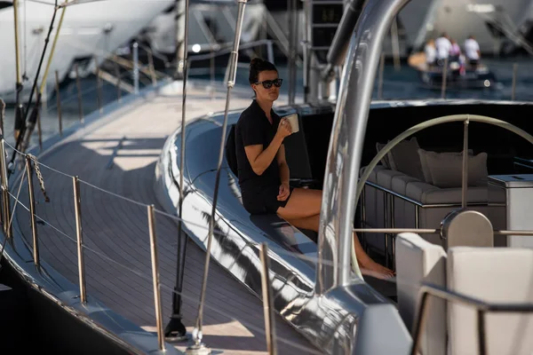 Монако, Монте-Карло, 28 сентября 2017: Девушка в солнцезащитных очках сидит на диване парусной яхты с кубком, яхтенный брокер, участники крупнейшей выставки яхт и лодок в Монако, мегаяхты — стоковое фото