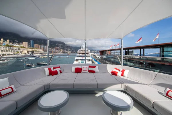 Přední paluba obrovské jachty v přístavu Monako za slunečného dne, památky Monte-Carlo a mnoho motorových člunů jsou na pozadí, salonek zóna pro chlazení, megayacht je zakotvena v přístavu — Stock fotografie