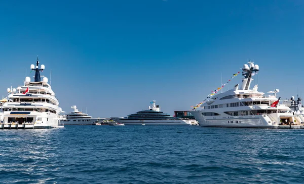 Una gran cantidad de enormes yates están en el puerto de Mónaco en el día soleado, Monte Carlo, la montaña está en el fondo, tablero brillante de la lancha, megayates están amarrados en el puerto deportivo, reflejo del sol en tablero brillante — Foto de Stock