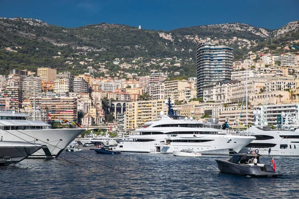 Muitos iates enormes estão no porto de Mônaco no dia ensolarado, megayachts são ancorados na marina, é um show de iate, Monte Carlo, habitação imobiliária está no fundo, placa brilhante do barco a motor — Fotografia de Stock