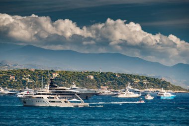 Güneşli bir günde liman yakınlarında bir sürü büyük yat vardır. Megayachtlar denize demirlemiştir. Monte Carlo adında bir yat fuarı vardır.