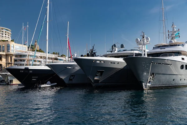 Una gran cantidad de enormes yates están en el puerto de Mónaco en el día soleado, Monte Carlo, la montaña está en el fondo, tablero brillante de la lancha, megayates están amarrados en el puerto deportivo, reflejo del sol en tablero brillante — Foto de Stock