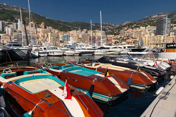 Muitos barcos a motor em filas estão no porto de Mônaco no dia ensolarado, Monte Carlo, montanha está no fundo, interior colorido do barco, estão ancorados na marina, reflexão do sol sobre placa brilhante — Fotografia de Stock