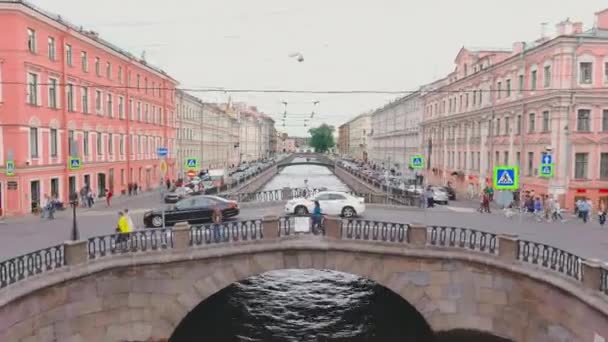 Rusia, San Petersburgo, 13 de junio de 2021: Un dron vuela sobre el Canal Griboyedov en un día nublado de verano, la gente camina a lo largo del terraplén y en puentes, los coches se mueven lentamente y se paran en atascos de tráfico — Vídeos de Stock