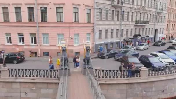 Rusland, St. Petersburg, 13 juni 2021: Een drone vliegt over het Griboyedov-kanaal op een bewolkte dag, een bankbrug, beroemde gouden leeuwen, mensen lopen langs de dijk en op bruggen, auto 's rijden langzaam — Stockvideo