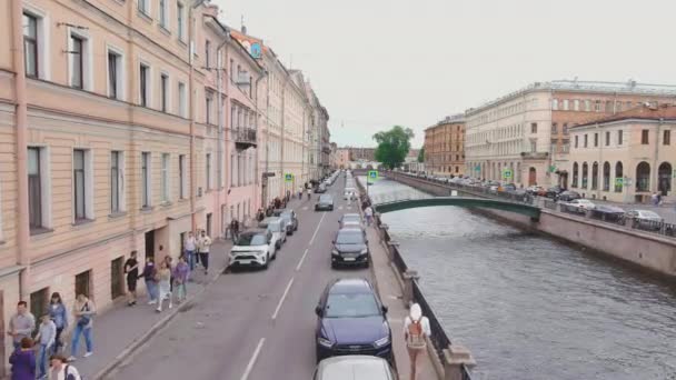 Rusland, St. Petersburg, 13 juni 2021: Een drone vliegt over het Griboyedov-kanaal op een bewolkte zomerdag, mensen lopen langs de dijk en op bruggen, auto 's bewegen langzaam en staan in files — Stockvideo