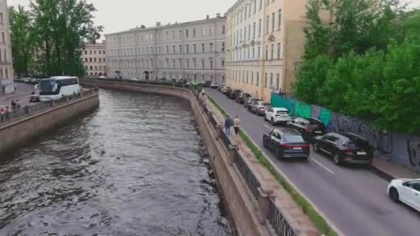 Rosja, Sankt Petersburg, 13 czerwca 2021 r.: Dron przelatuje nad Kanałem Gribojedowa w pochmurny letni dzień, ludzie chodzą wzdłuż wału i po mostach, samochody poruszają się powoli i stoją w korkach — Wideo stockowe