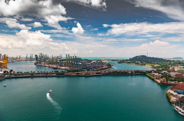 De grootste logistieke haven van Singapore, veel kranen om containers te verplaatsen, enorme vrachtschepen op de achtergrond, winkelcentra en wolkenkrabbers omringd door, entertainment eiland in de buurt — Stockfoto