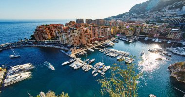 Port Fontvieille 'in panoramik görüntüsü - Monaco, Monaco Ville' in manzarası, azur suyu, güneş ışığı, güneşli bir günde liman, lüks daireler, bir sürü yat ve tekne, dağ manzarası