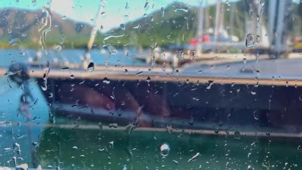 Крупный план через влажное стекло экипажа огромной лодки моет парусную яхту в ясную солнечную погоду, она готовит роскошную лодку для приема гостей — стоковое видео