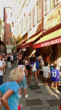 Fransa, Nice, 15 Temmuz 2018: Açık güneşli bir yaz gününde futbol takımının zaferini kutlayan taraftarlar kafe masalarında dans ediyor, insanlar eğleniyor ve gürültü yapıyor
