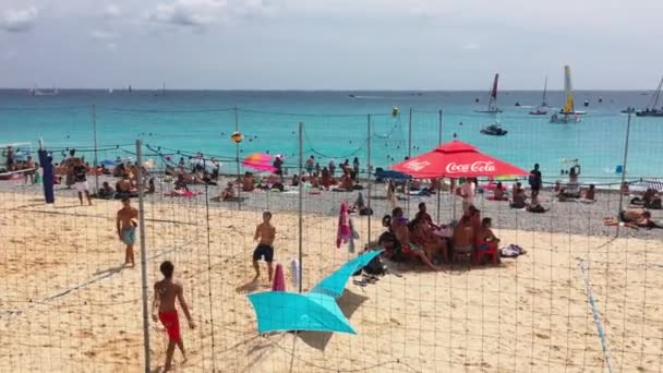 Frankrike, Nice, 21 Juli 2018: Människor spelar volleyboll på stranden i en klar solig dag, Många människor, turkost vatten, paraplyer från solen, en lokal attraktion - Promenade des Anglais — Stockvideo