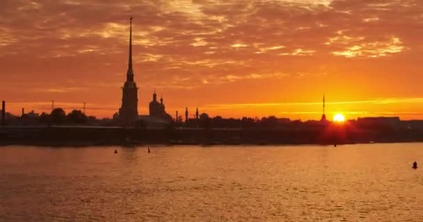 Прохід у часі фортеці Петра і Павла в Петербурзі на світанку, тихі хвилі річки Неви, золотий шпиль з ангелом на вежі, рожеве і помаранчеве небо, Росія — стокове відео
