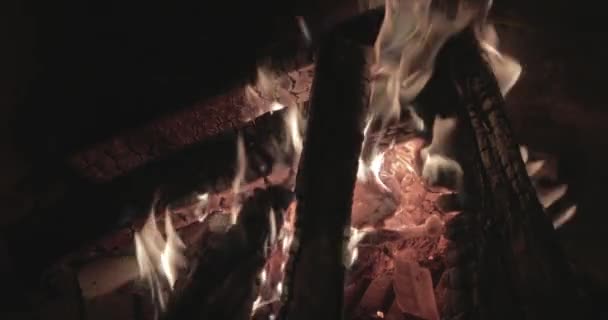 Zblízka záběry velkého ohně s palivem v noci, cihlové stěny krbu, táborák hoří, jiskry, plameny ohně, je spousta červených dřevěných uhlíků, krb, pára a kouř, — Stock video